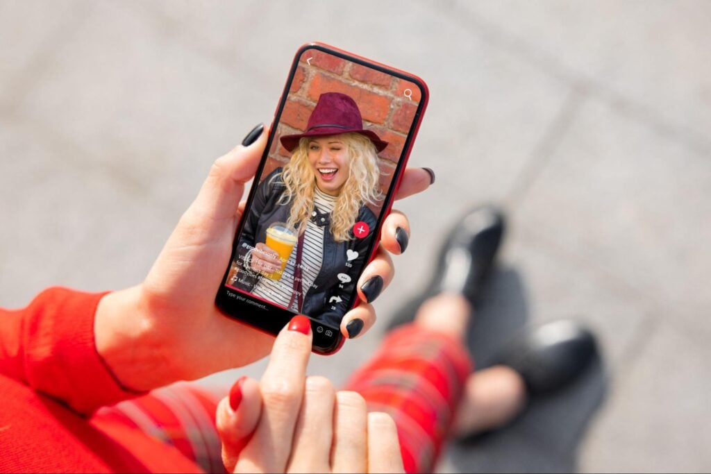 On Hook Agency's site, a user in red scrolls content on their smartphone; a smiling woman with a drink appears, embodying business inspiration.