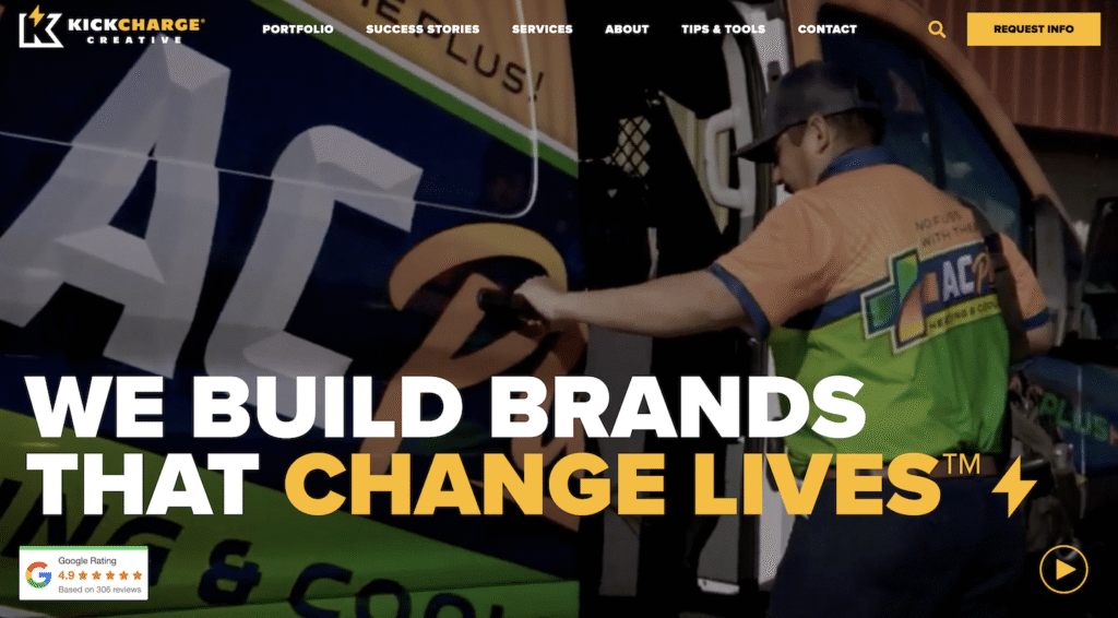 A skilled technician, outfitted in a vibrant uniform, expertly applies branded graphics to a van—demonstrating the proven expertise of one of the industry’s top plumbing marketing agencies. Bold headline: "WE BUILD BRANDS THAT CHANGE LIVES™." The KickCharge Creative logo and navigation menu are prominently displayed at the top.