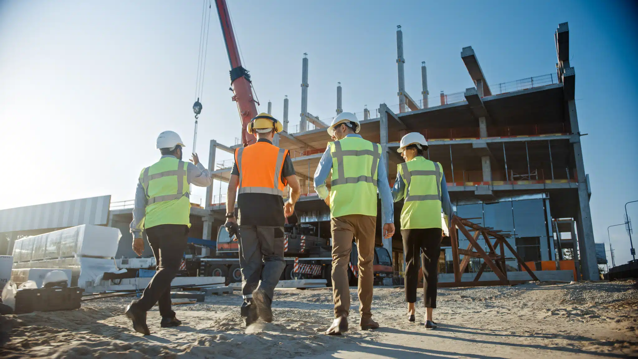 On the Hook Agency's website: Four construction workers in hard hats and reflective vests approach a construction site. A crane looms over the incomplete structure, all set against a clear blue sky—a vivid illustration of how effective marketing strategies are crafted with precision and intent.