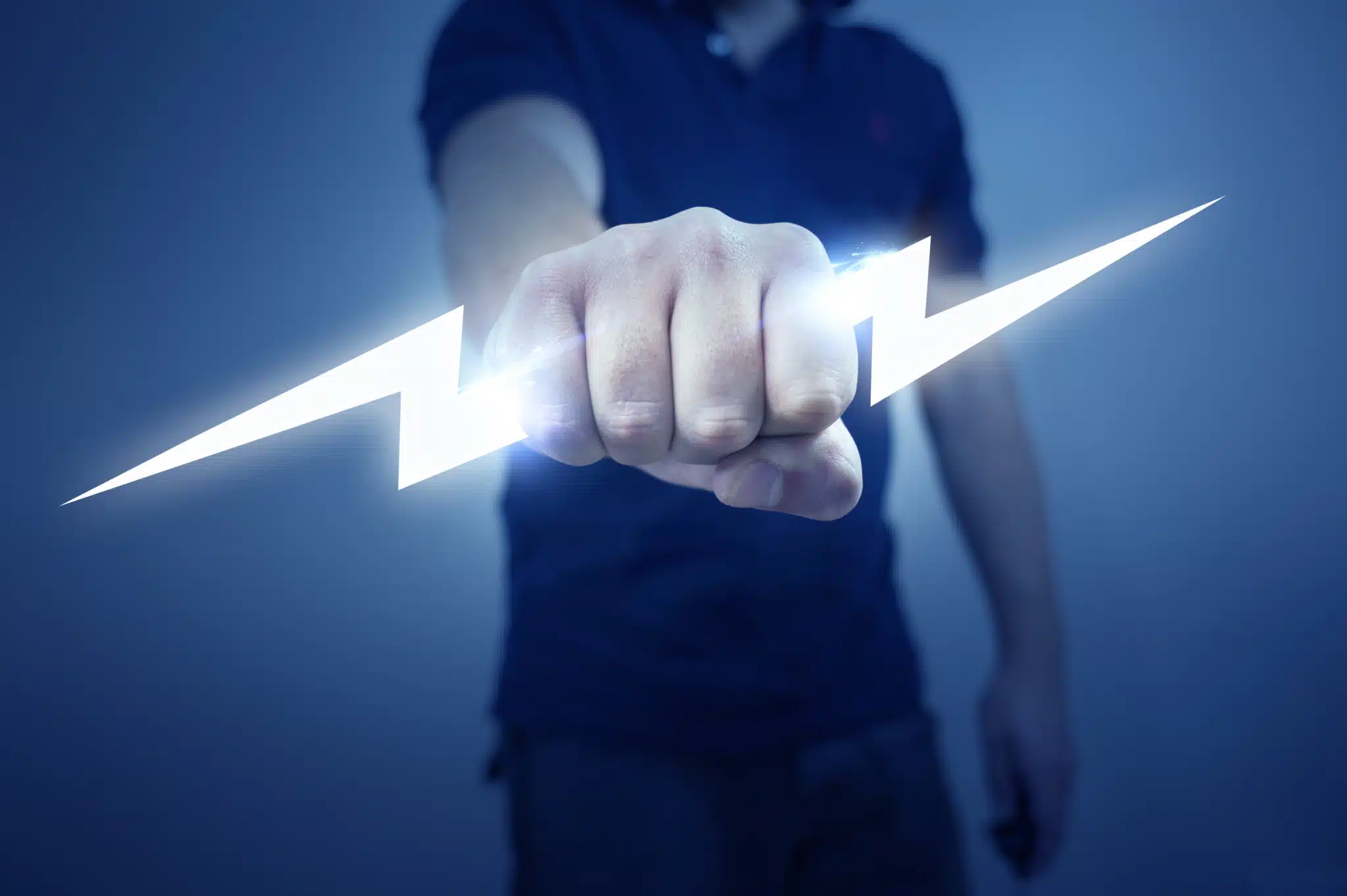 An individual grips a glowing lightning bolt against a striking blue background, embodying the dynamic expertise of an electrician. The bolt's intense light illuminates their hand, creating a powerful and dramatic visual about Electrician SEO Marketing. Dressed in a dark shirt, the obscured face adds to the image's potent sense of energy and authority.