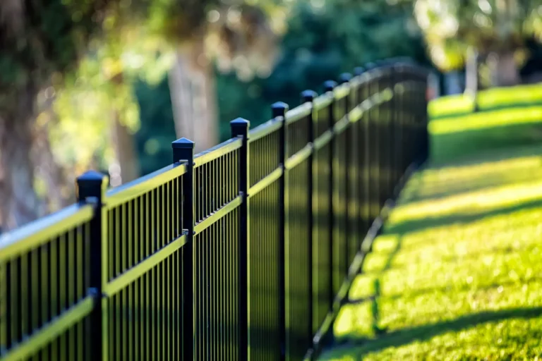 Discover the superior craftsmanship of our black metal fence, designed for both durability and style. Installed diagonally across a sunlit lawn, it creates an eye-catching pattern of light and shadow. The natural backdrop of greenery and towering trees further amplifies the aesthetic appeal, showcasing why our fence solutions stand out in any setting.
