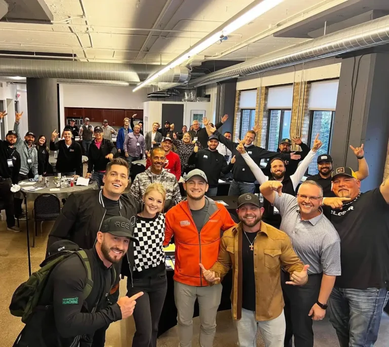 In a lively office setting, a group of enthusiastic individuals gathers, exuding vibrant energy as they celebrate their careers. Their expressions of joy and excitement fill the room, creating an atmosphere that resonates with achievement and camaraderie. Tables and chairs serve as the backdrop to this dynamic scene, highlighting the spirited workplace culture at Hook Agency.