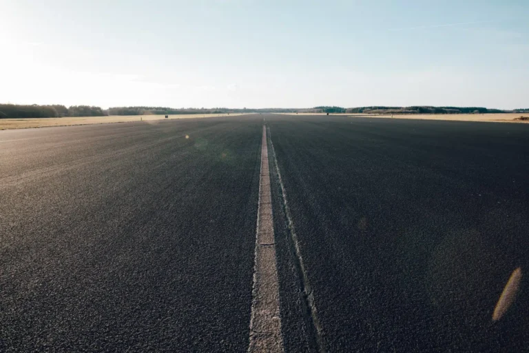 An impeccably paved runway extends under a clear sky, marked by a subtle central white line. The flat, open landscape with few distant trees creates an ideal setting for effective PPC testing scenarios.