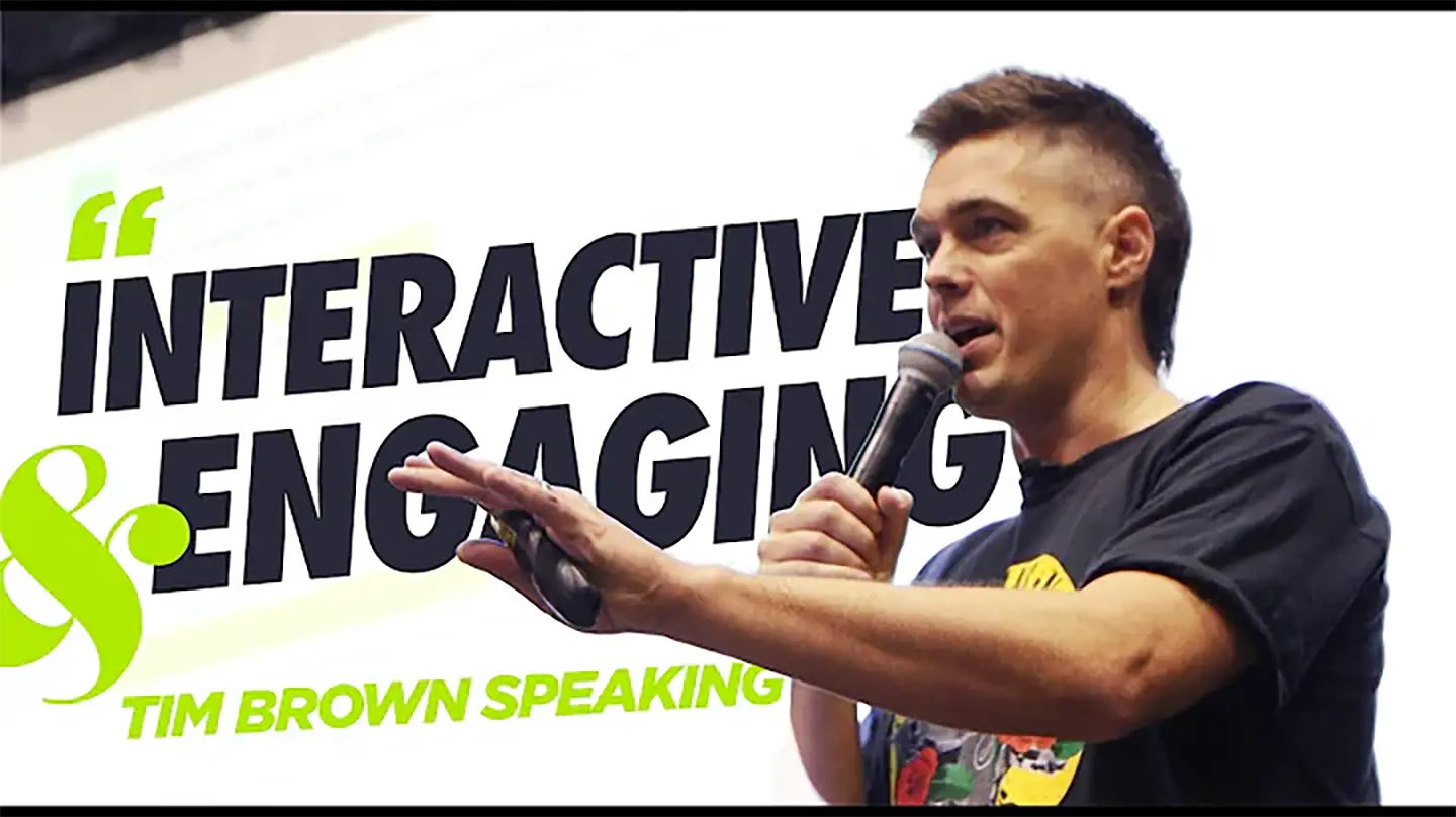 On stage, Tim Brown captivates the audience, microphone in hand. The backdrop boldly proclaims "INTERACTIVE & ENGAGING," with his name, "TIM BROWN SPEAKING," highlighted in bright green.