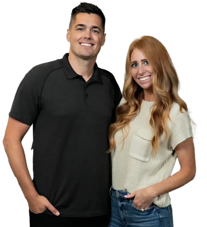 A man in a black polo shirt and a woman with long red hair in a beige top stand confidently, conveying a professional yet approachable demeanor, ready to address all of your tree service needs.